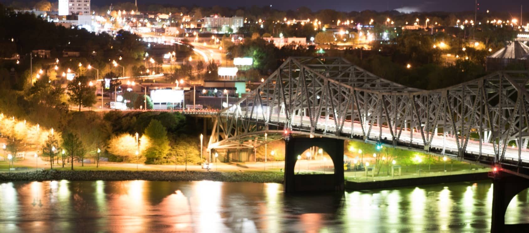 Brug over rivier in Muscle Shoals bij nacht met stadslichten