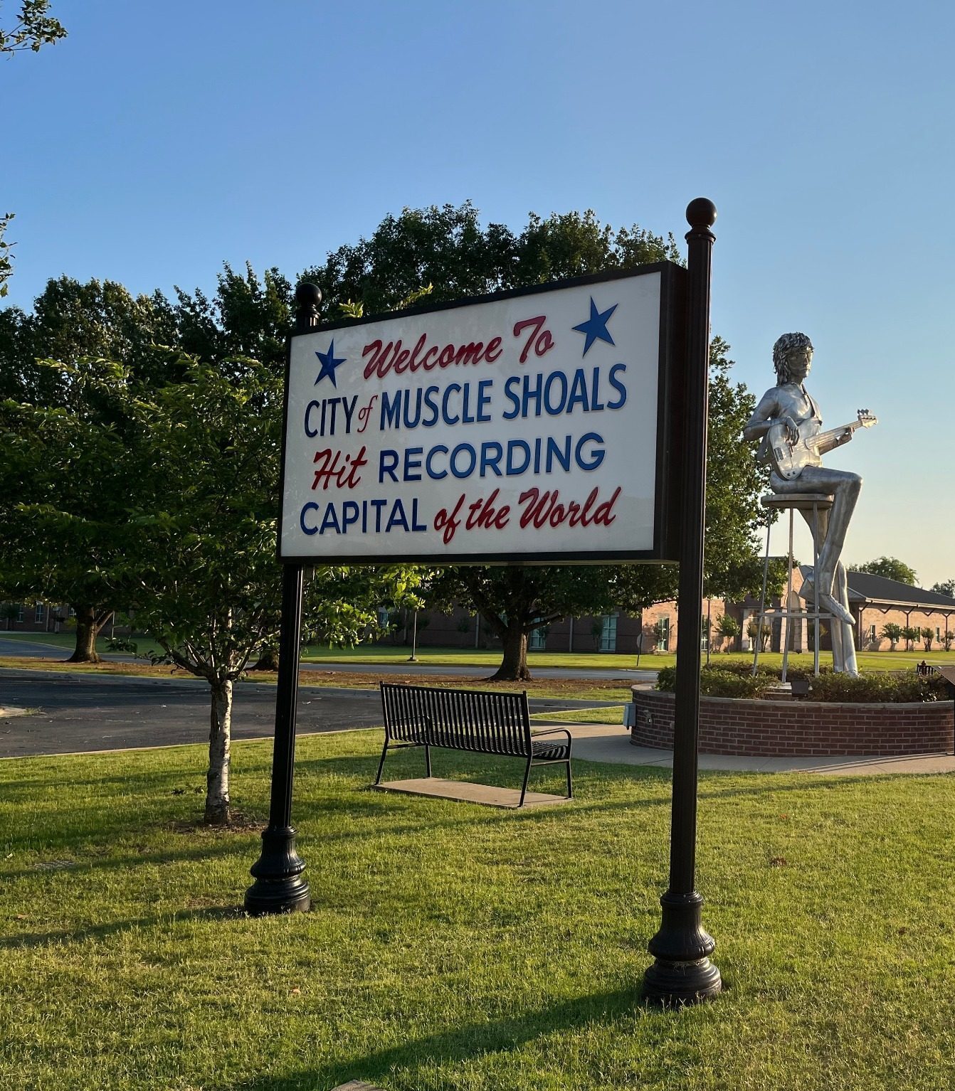 Welkomsbord en standbeeld in Muscle Shoals met grasveld en weg